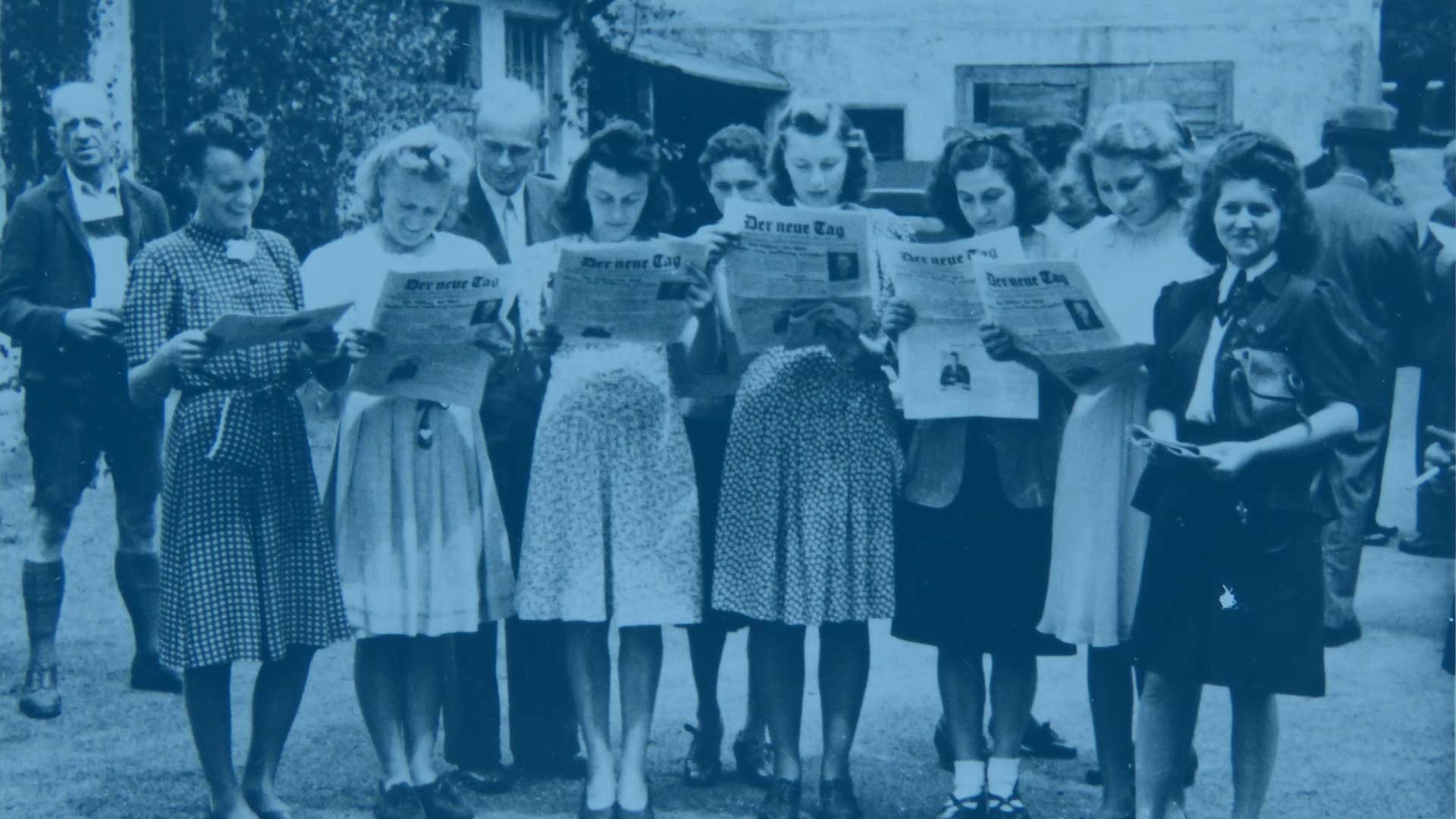 Gruppe von Frauen aus den 40er Jahren mit der Tageszeitung „Der neue Tag“ in den Händen.