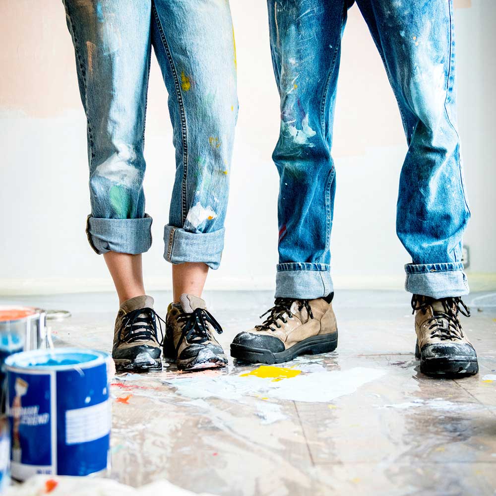 Vier mit Farbe bespritzte Beine in Jeans für die Beilage „Bauen, sanieren, renovieren“ von Oberpfalz Medien.