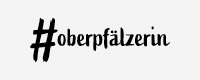 Logo von #oberpfälzerin, schwarze Schrift auf grauem Grund.