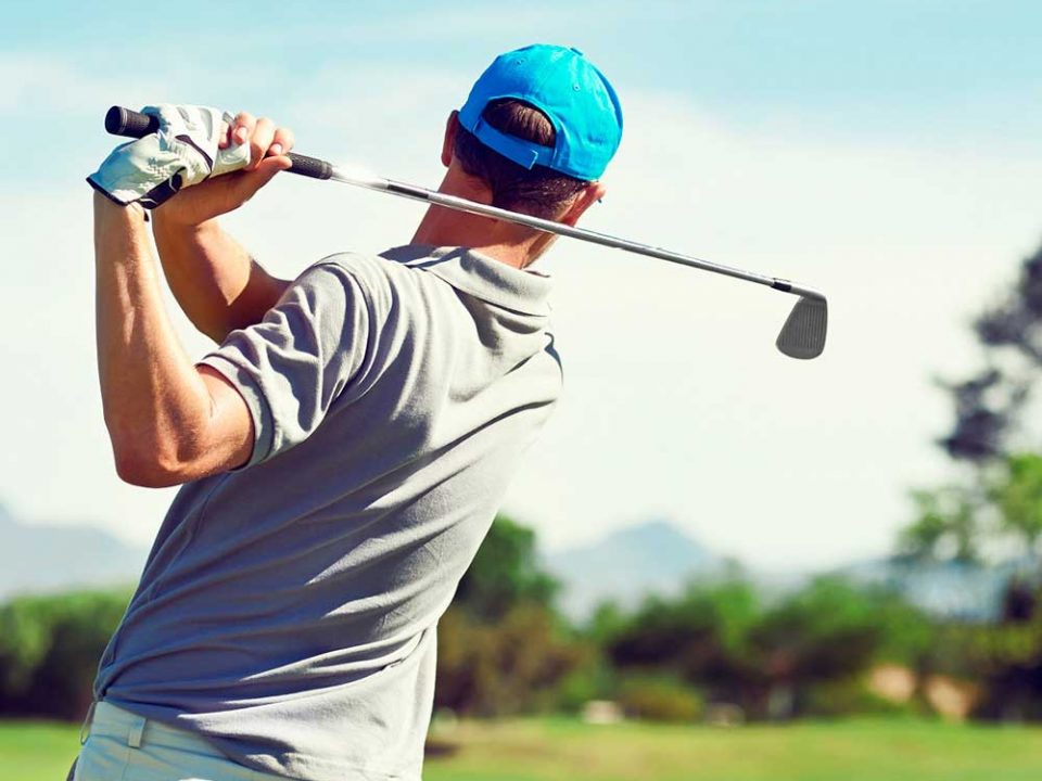 Ein Golfer von hinten, der seinen Golfschläger schwingt.
