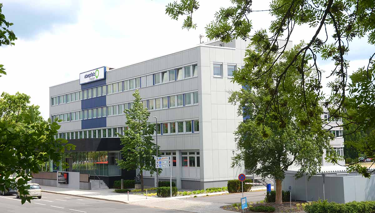 Verlagsgebäude von Oberpfalz Medien in Weiden von außen, grüne Bäume, Straße.