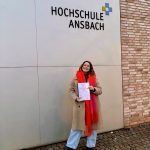 Eine junge Frau hält eine Bachelorarbeit in der Hand.