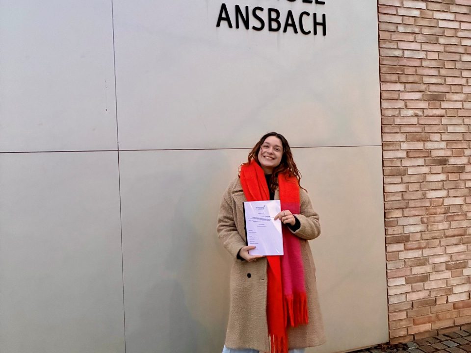 Eine junge Frau hält eine Bachelorarbeit in der Hand.
