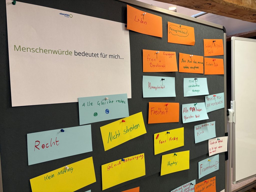 Was bedeutet Menschenwürde? Eine Tafel mit bunten Karten, auf denen Begriffe zum Thema Menschenwürde stehen